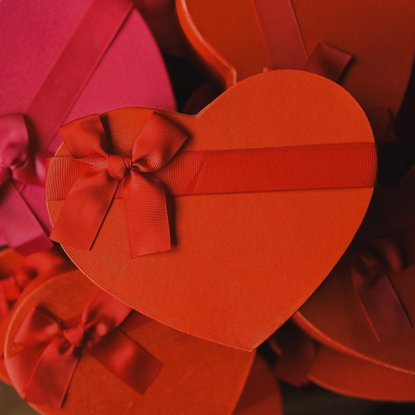 Heart-shaped gift boxes with ribbons in red and pink colors.