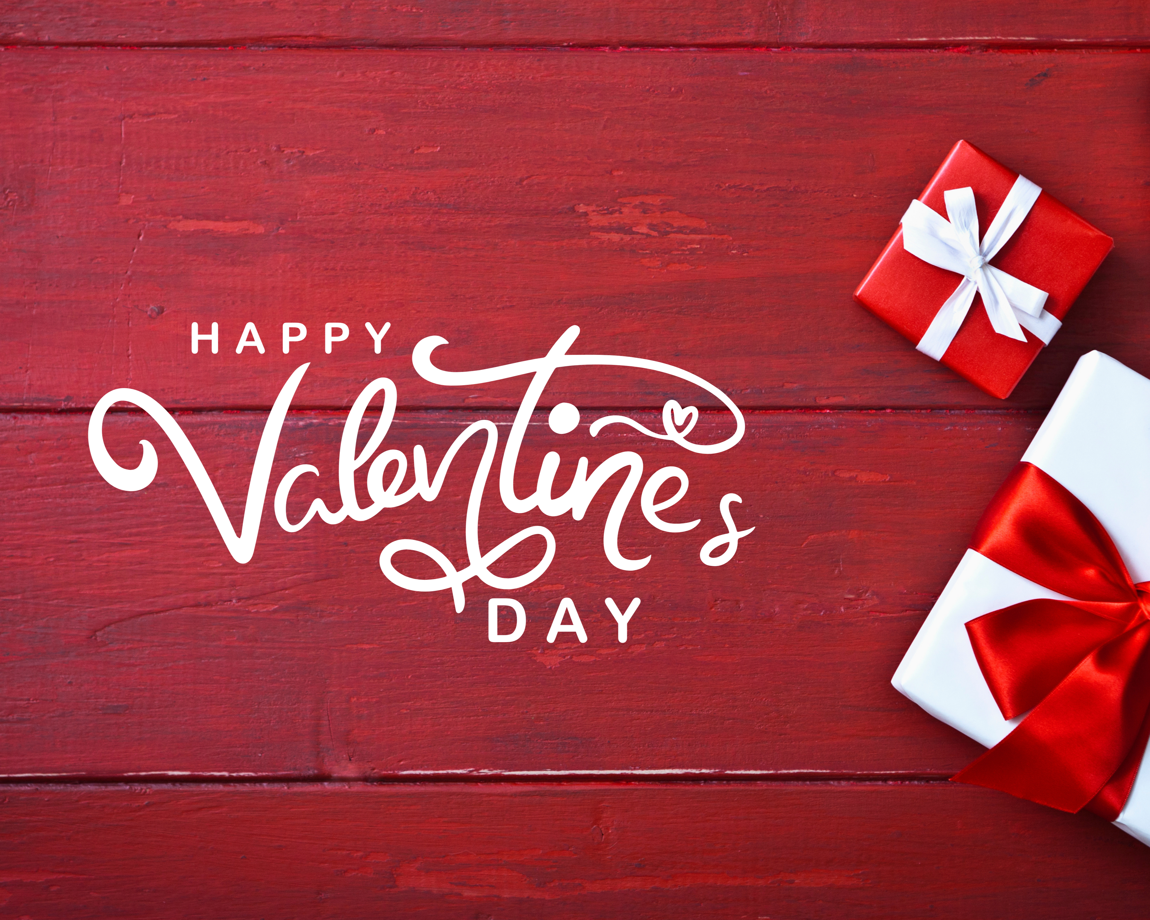 Happy Valentine's Day text on a red wooden background with gift boxes.