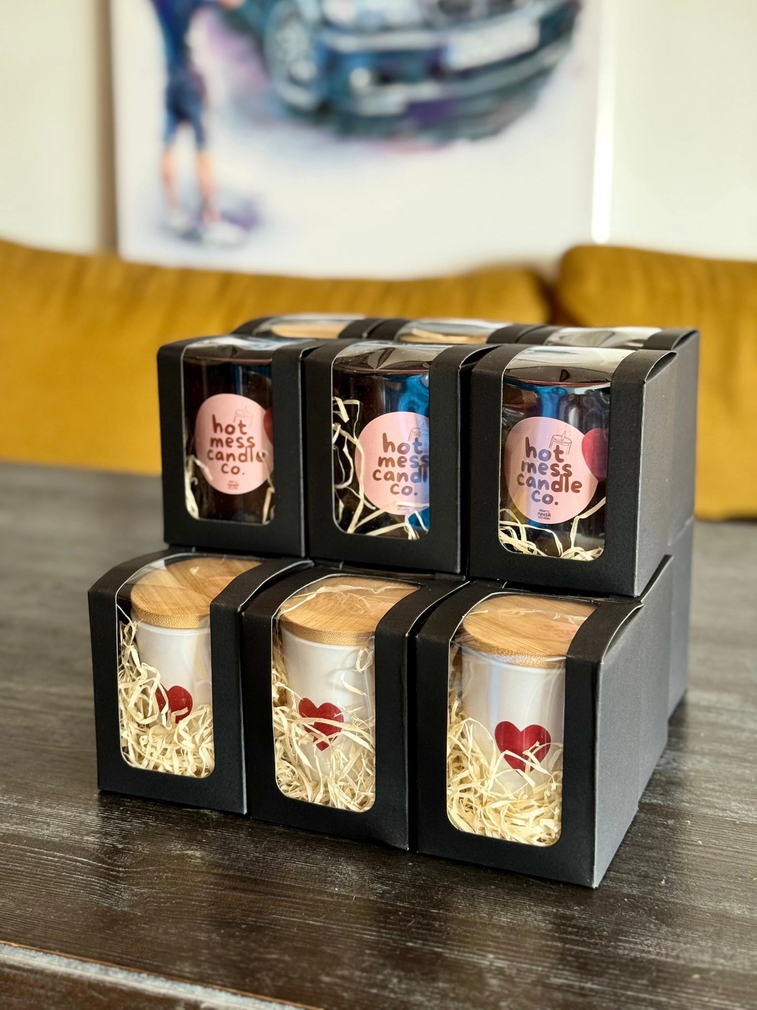 Set of candles in black boxes on a wooden surface with a blurred background