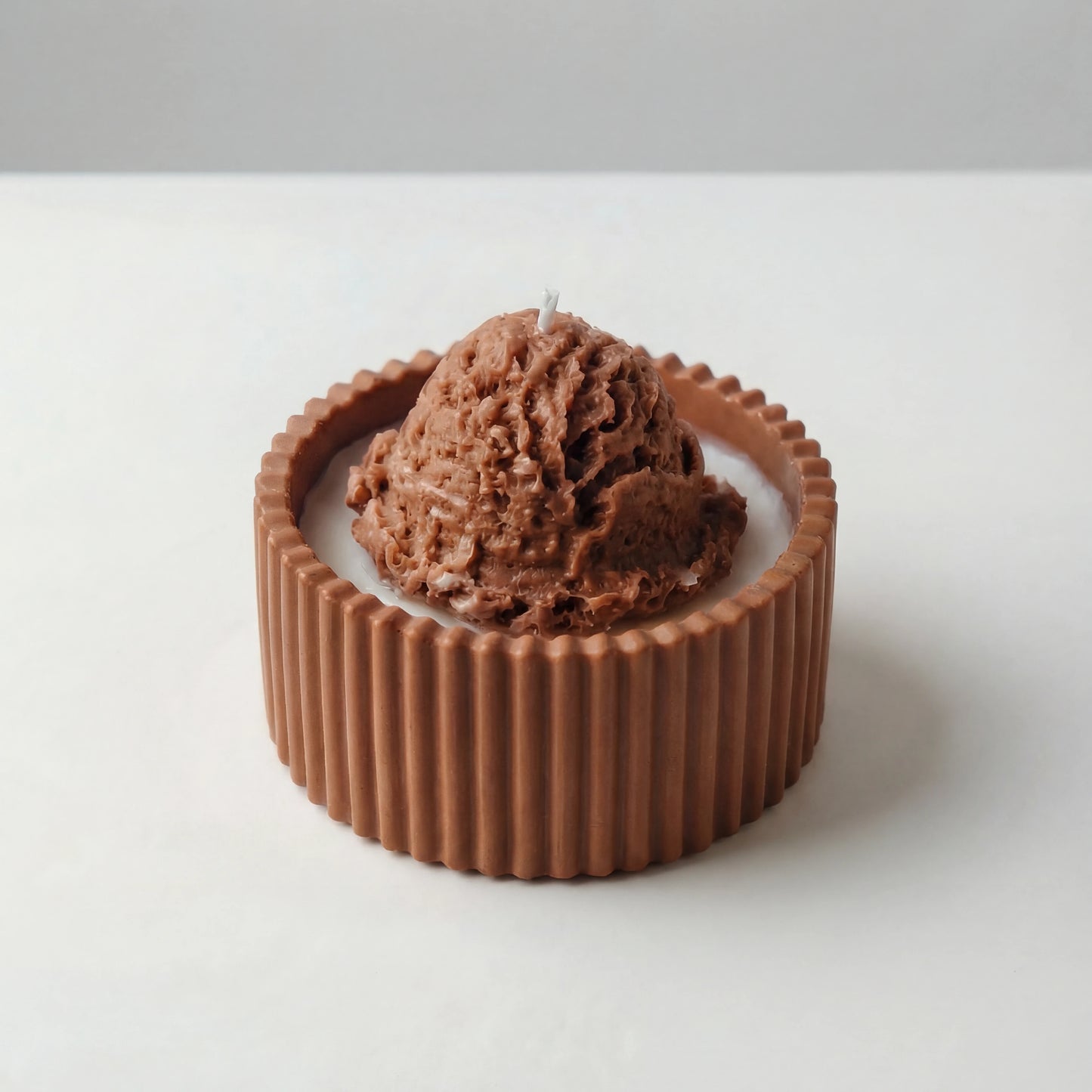 Candle shaped as a chocolate ice cream scoop in a chocolate shell on a white background