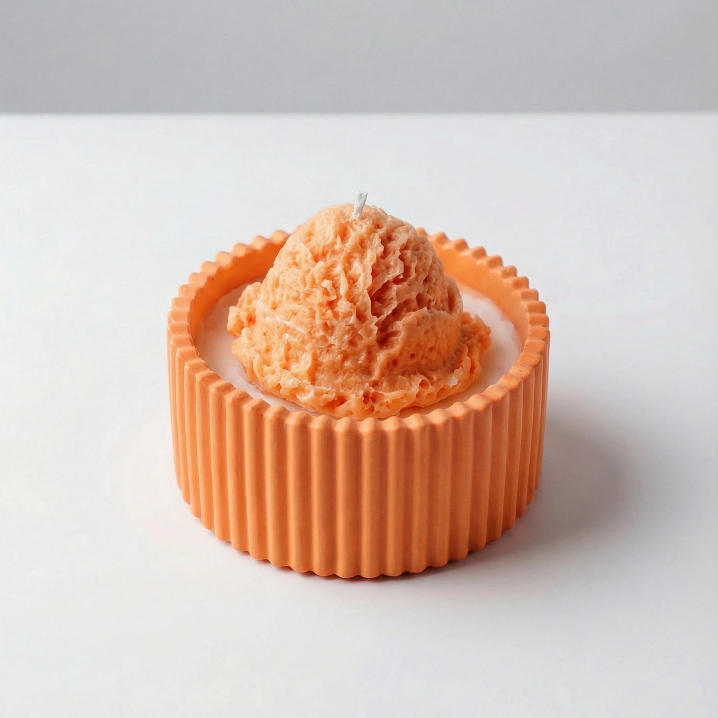 Orange ice cream candle with textured candle container design on a white background