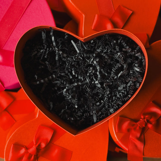 Heart-shaped red gift box with black crinkled paper inside